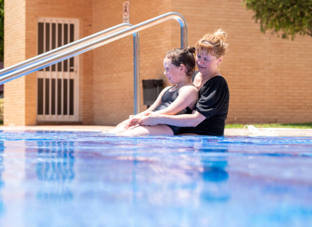 une femme de race blanche de 40 ans embrasse une fille de 7 ans, s’allonge dans une piscine extérieure et profite. journée ensoleillée d’été. - female 8 9 years child excitement photos et images de collection