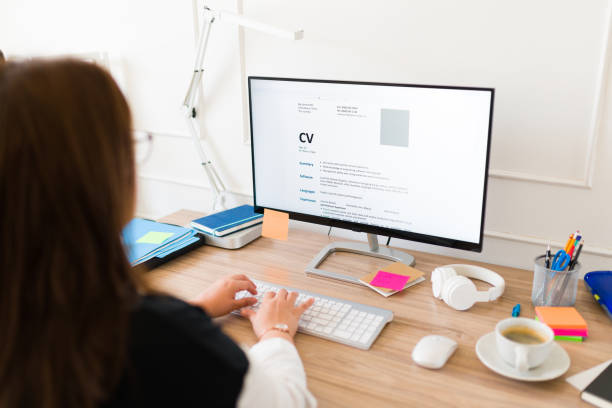 Woman seen from behind working on her new resume Professional woman seen from behind updating her curriculum or resume on the computer while applying for a new job good cv stock pictures, royalty-free photos & images
