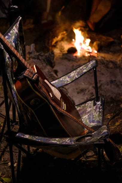 istock Acoustic guitar in camping chair with fire flame on background. summer camping 1508977668