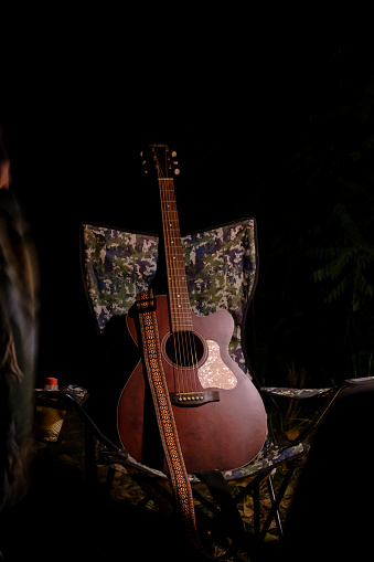 Acoustic guitar resting in camping chair on background dark with copy space. classic guitar