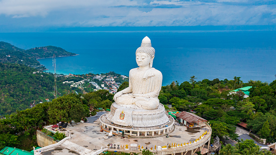 Beautiful Phuket white Big Buddha statue on blue sky background. Aerial view of Big Buddha viewpoint at sunrise in Phuket province, Thailand.