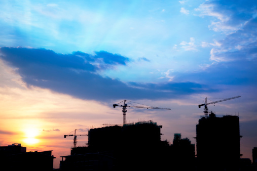 Urban scenic - Industrial construction cranes and building silhouettes at sunset