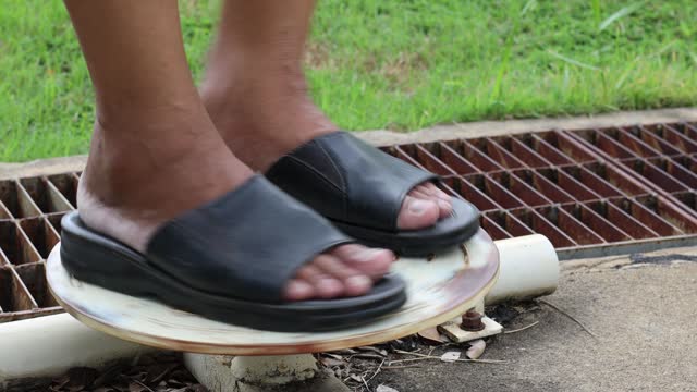 A close-up view of a foot of a Thai man doing exercises on an old white steel exercise bike.