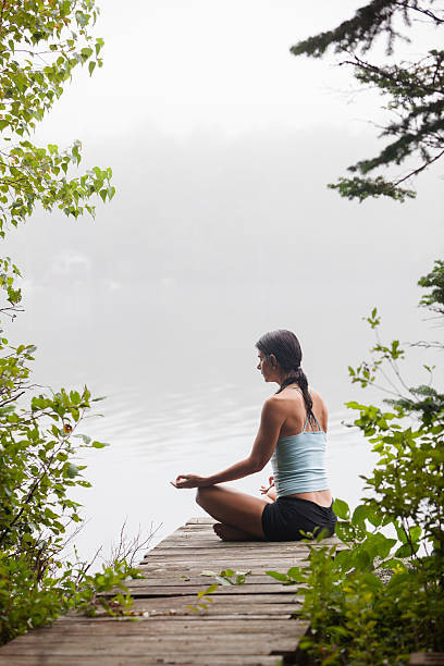 istock Woman meditating on dock by lake 150909718