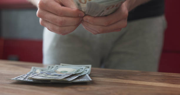 istock front shot of man counting dollars on wood table 1509103760