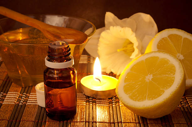 Lemon and honey aromatherapy Essential oil, lemon, honey in the bowl, burning candle and flower on the mat aromatherapy oil photos stock pictures, royalty-free photos & images