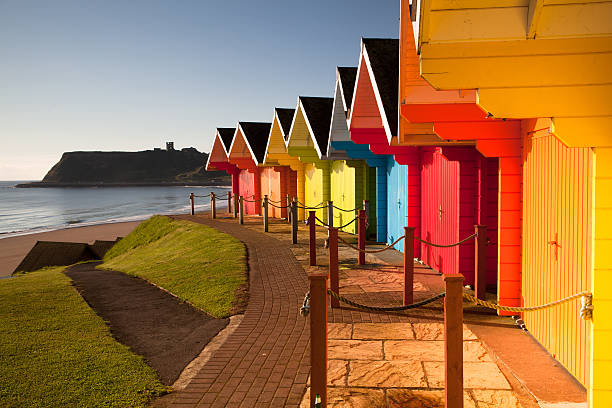 Colorful beach huts near ocean Beach huts at sunrise in Great Britain staycation photos stock pictures, royalty-free photos & images