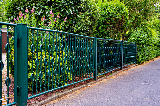 Green metal fence next to road in Germany.