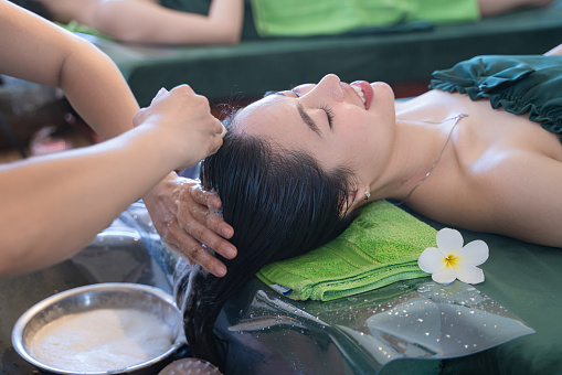 Young Vietnamese girl is head washing and hair care in spa