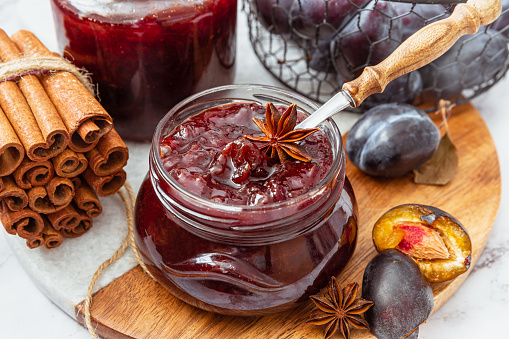 Homemade plum jam in a glass jar on a wooden background.Selective focus