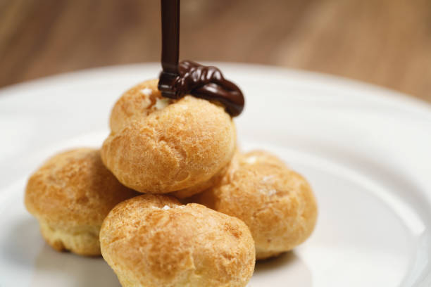 pour chocolate on profiteroles on plate closeup