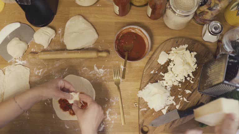 High angle view of women's hands kneading dough and grating cheese while making delicious Italian Panzerotti