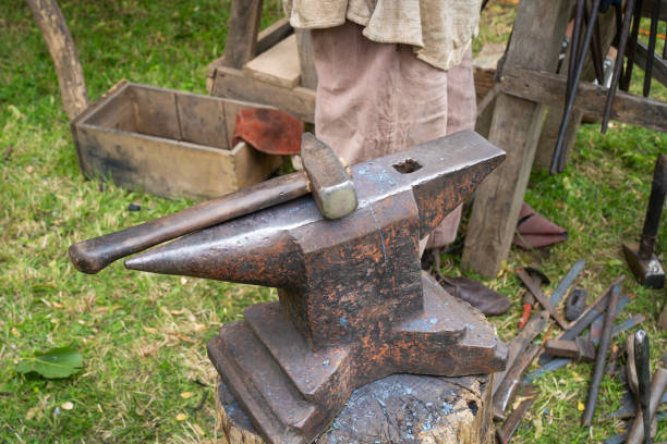 istock Blacksmith's anvil with hammer in the background with metal tools 1509221133
