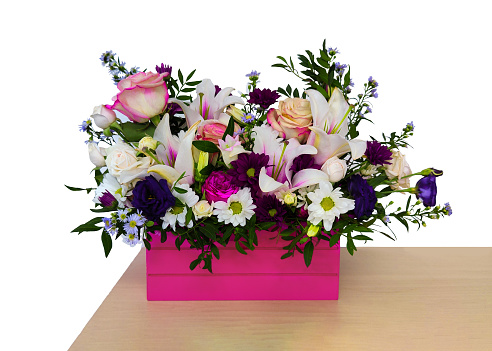 Fresh flowers in pink wooden box, bright bouquet on white backdrop on light table corner. Floral composition of summer plants arranged stylishly with taste. Celebration or birthday gift. Copy space