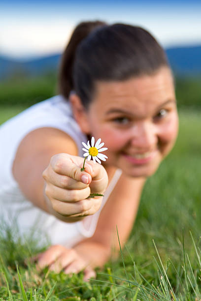 istock Cute smiling girl showing a daisy on the grass 150923024