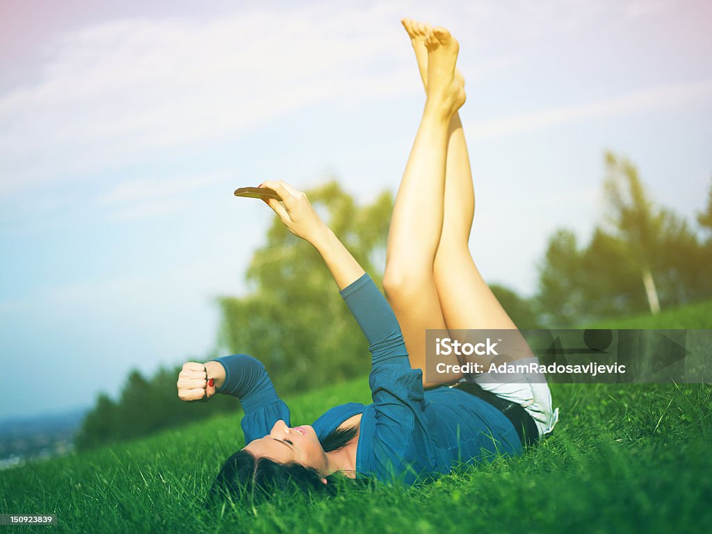 Good news Young woman using mobile phone in park Adult Stock Photo