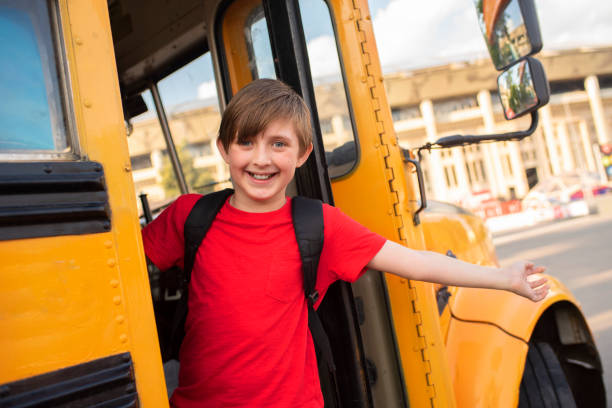 istock happy boy with backpack getting out or getting into the yellow school bus 1509245696