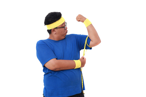 Asian overweight man in sportswear measuring his arm with measuring tape. Isolated on white
