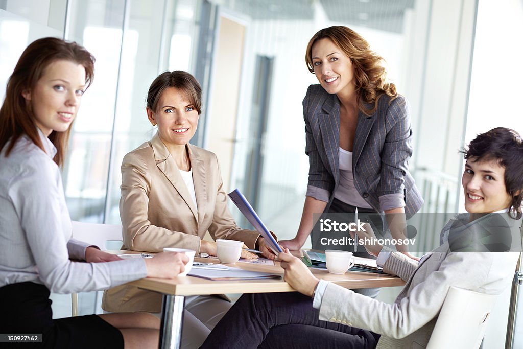 Colleagues Image of four successful businesswomen looking at camera at meeting Adult Stock Photo