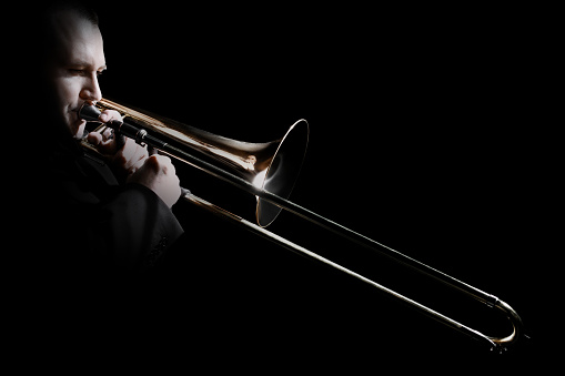 Trombone player. Trombonist playing jazz musician. Man playing trumpet brass instruments isolated on black