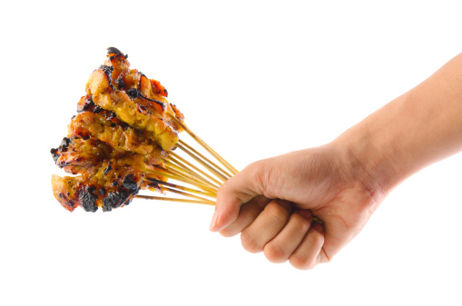 Asian man hand holding a bunch barbecued satay chicken over white background