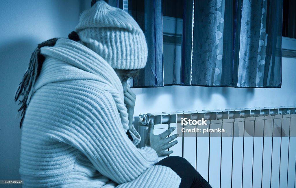 Woman freezing at home Woman freezing at home, checking the radiator Cold Temperature Stock Photo