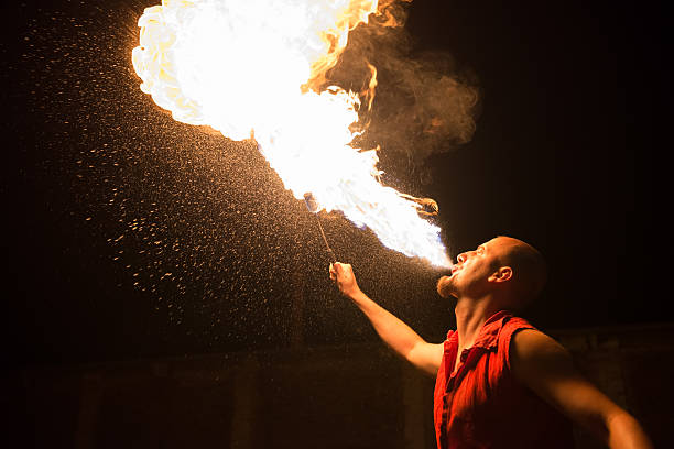 Performer breathing fire against a black background stock photo
