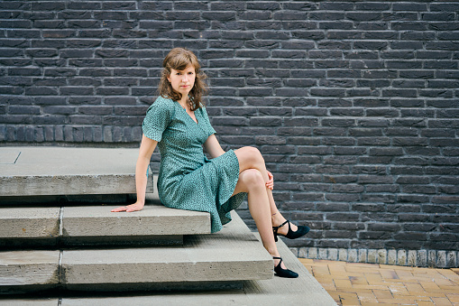 Woman in turquoise retro summer dress. Portraits in cityscape full length