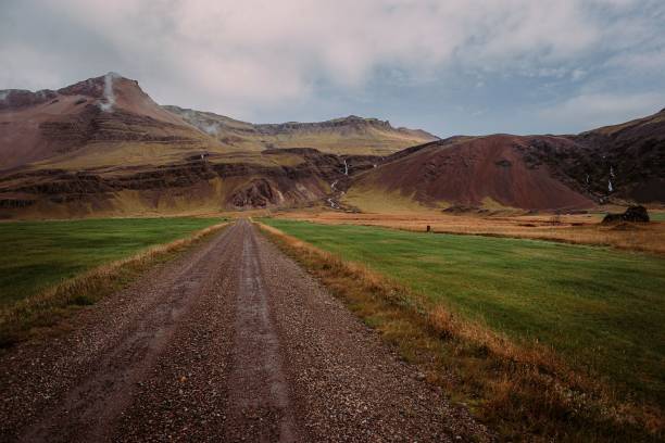 istock Icelandic empty dirt road between grass and mountains in the background 1509440270