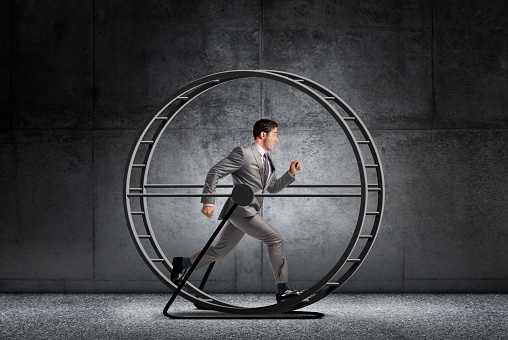A businessman runs in a circles on a circular treadmill.