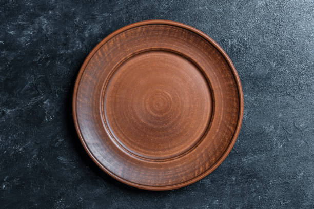 istock Empty flat plate of red clay over black background . Top view, closeup . Rough ceramic bowl background with copy space 1509448061