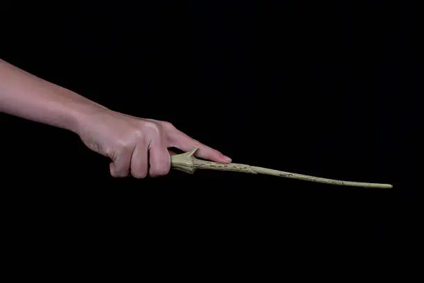 Hand holding wand with black background.