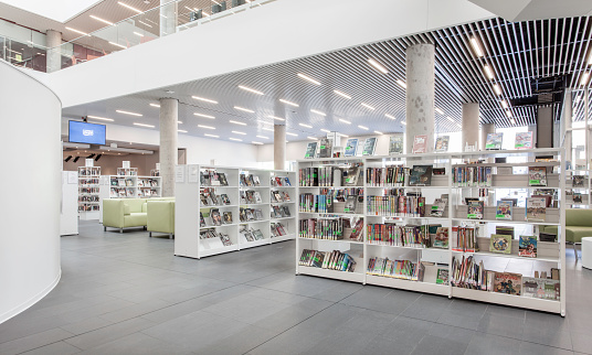 Halifax Central Library bookshelves near entrance with stairs to second floor in background.