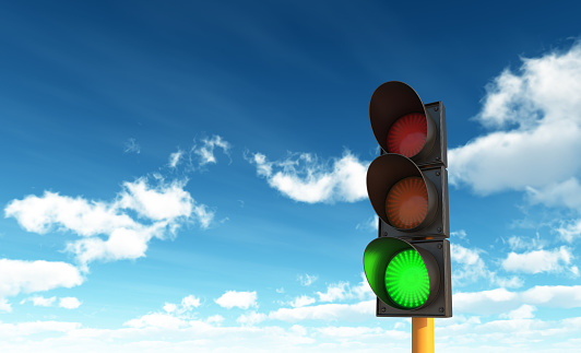 Simple image of a modern traffic light, showing green, on a street in downtown Boston.