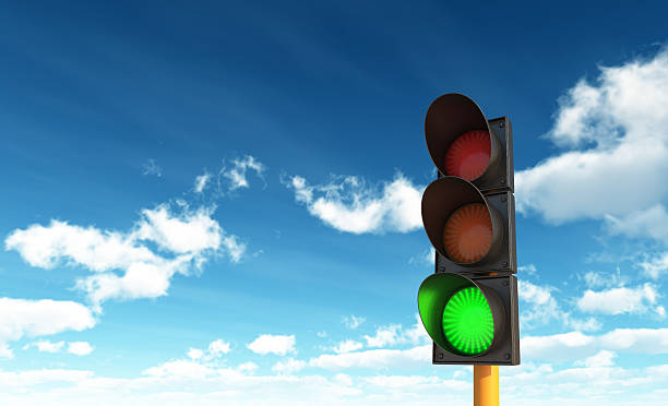 Green traffic light in front of a blue sky with clouds Green Traffic Lights against Blue Sky Backgrounds with clipping path green light stoplight stock pictures, royalty-free photos & images