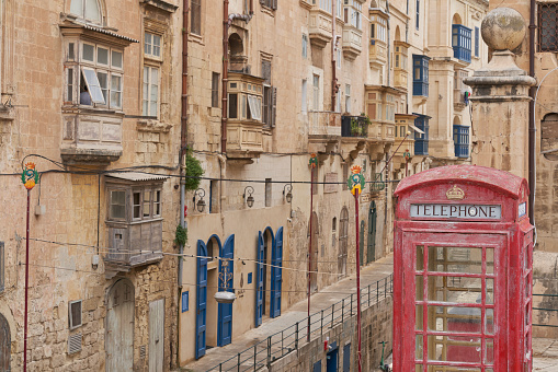 Valetta, Malta - June 6, 2023: Red telephone box amongst historic buildings in the city of Valetta in Malta