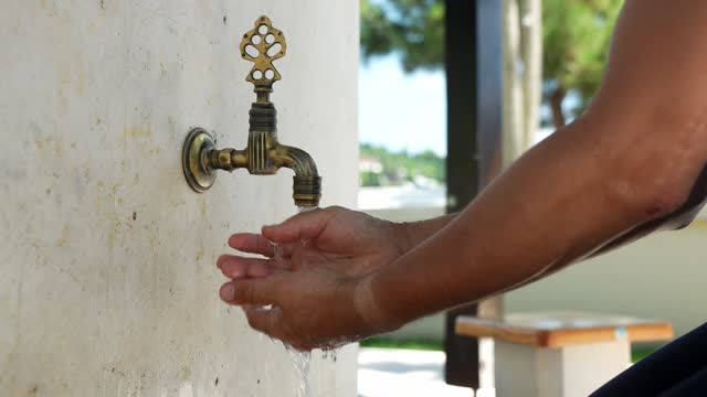man washing his hands in the mosque's faucet