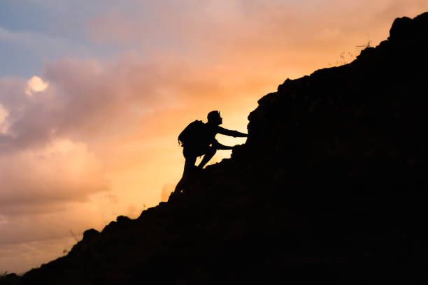 Male hiker climbing steep mountain. Male hiking up the steep mountain at sunset. climbing up a hill stock pictures, royalty-free photos & images