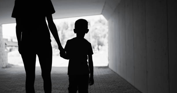 Single parent mom walking with child to the light at the end of tunnel. stock photo