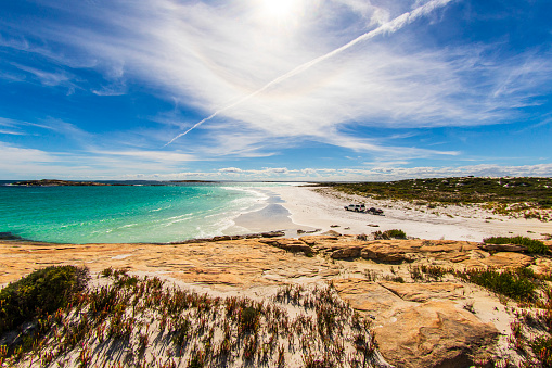 Picturesque view of car driving along beach and coastline in remote Western Australia on a sunny day.