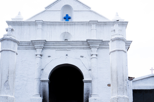 Facade of white Chapel of Calvary or Capilla del Calvario across the market square from the Church of Santo Tomas in Chichicastenango, Guatemala