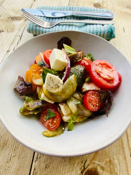 полезный летний салат с томатным фетта, базиликом и луком на деревянном столе - fetta cheese стоковые фото и изображения