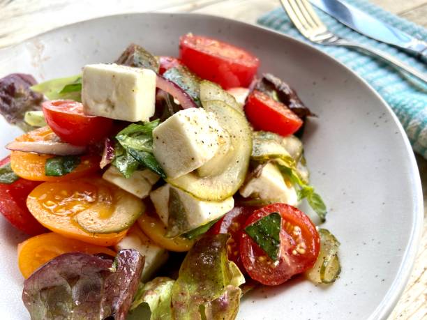 полезный летний салат с томатным фетта, базиликом и луком на фоне тарелки из дерева - fetta cheese стоковые фото и изображения
