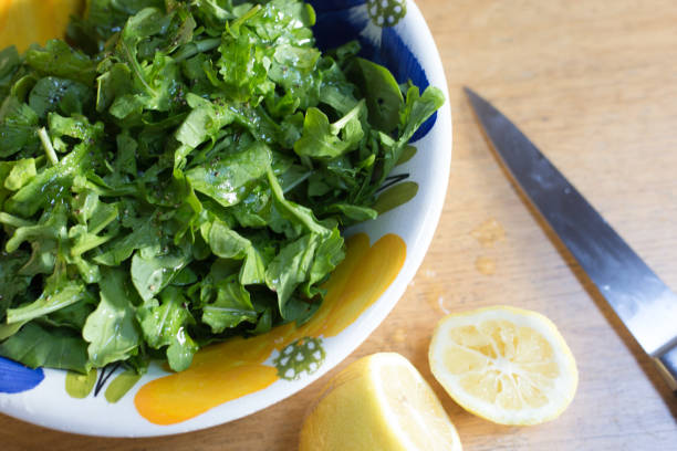 Overhead View: Arugula Salad in Colorful Bowl, Cut Lemon, Knife