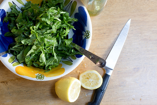 Overhead View: Arugula Salad in Colorful Bowl, Cut Lemon, Knife