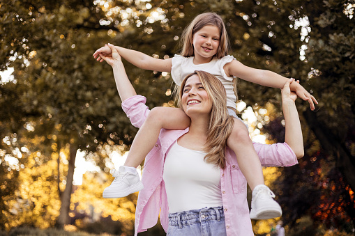 Joyful Family Having Fun With Her Daughter Outdoor. Family, Leisure and People Concept