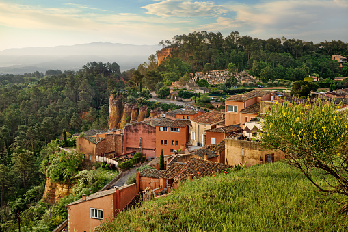 Roussillon, Provence-Alpes-Cote d'azur, France: sunrise landscape of the ancient village, red ochre rocks and green valley in the Luberon Natural Park