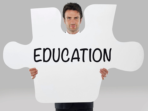 Businessman holding a missing piece of a puzzle with “Education” text