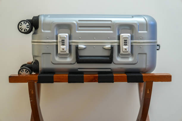 Silver suitcase on wooden luggage rack isolated on white background