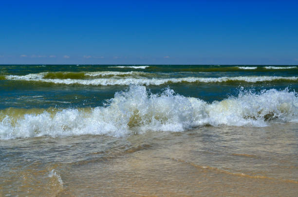 les vagues de la mer baignent la plage contre un ciel bleu. paysage sur une plage sauvage. la mer en été. - prop wash photos et images de collection